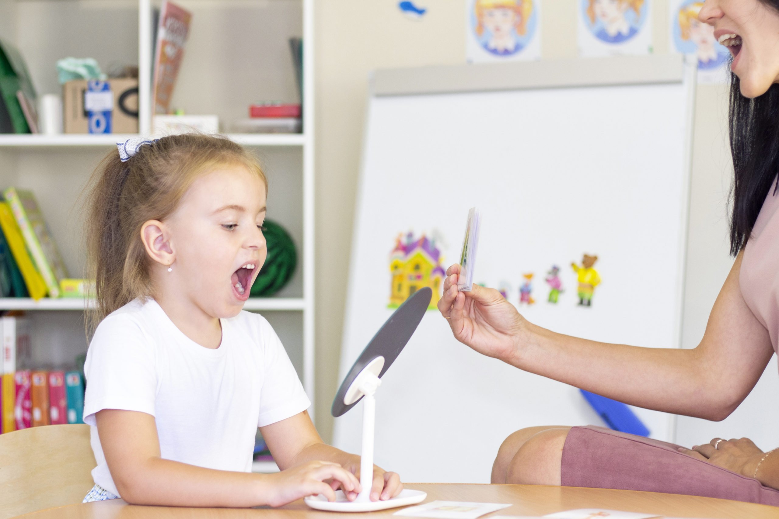 developmental and speech therapy classes with a child-girl. Speech therapy exercises and games with a mirror and cards